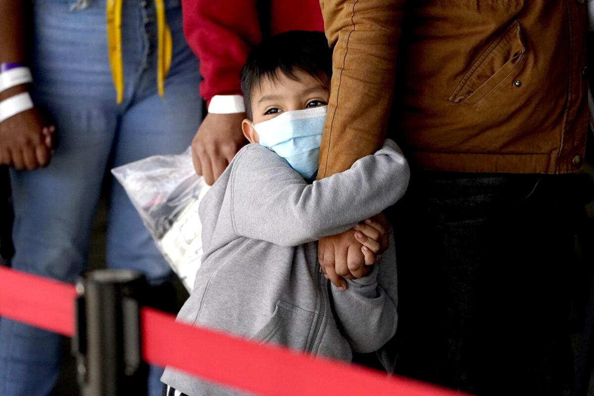 Migrant child clutching woman's arm