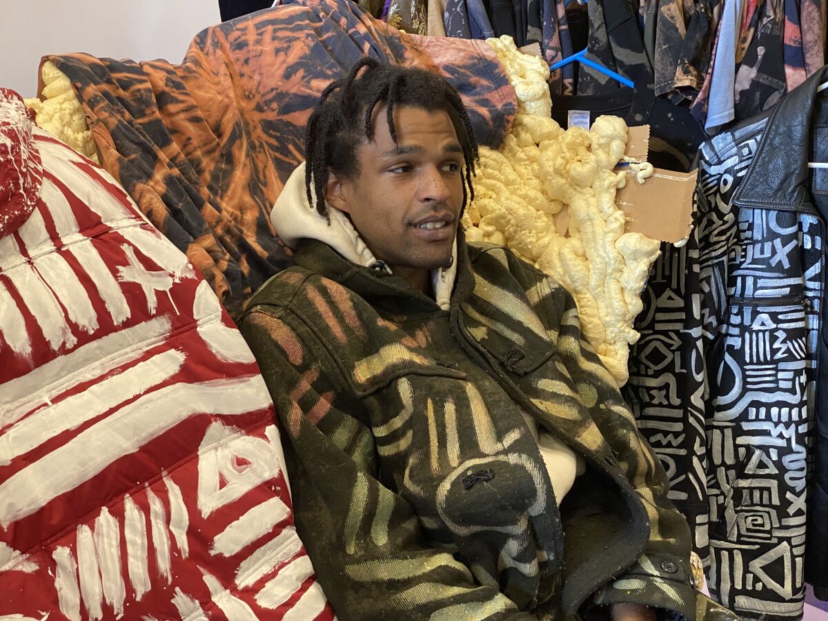 Procter sits in his Seattle store among clothes he designed and bleached with distinctive patterns.
