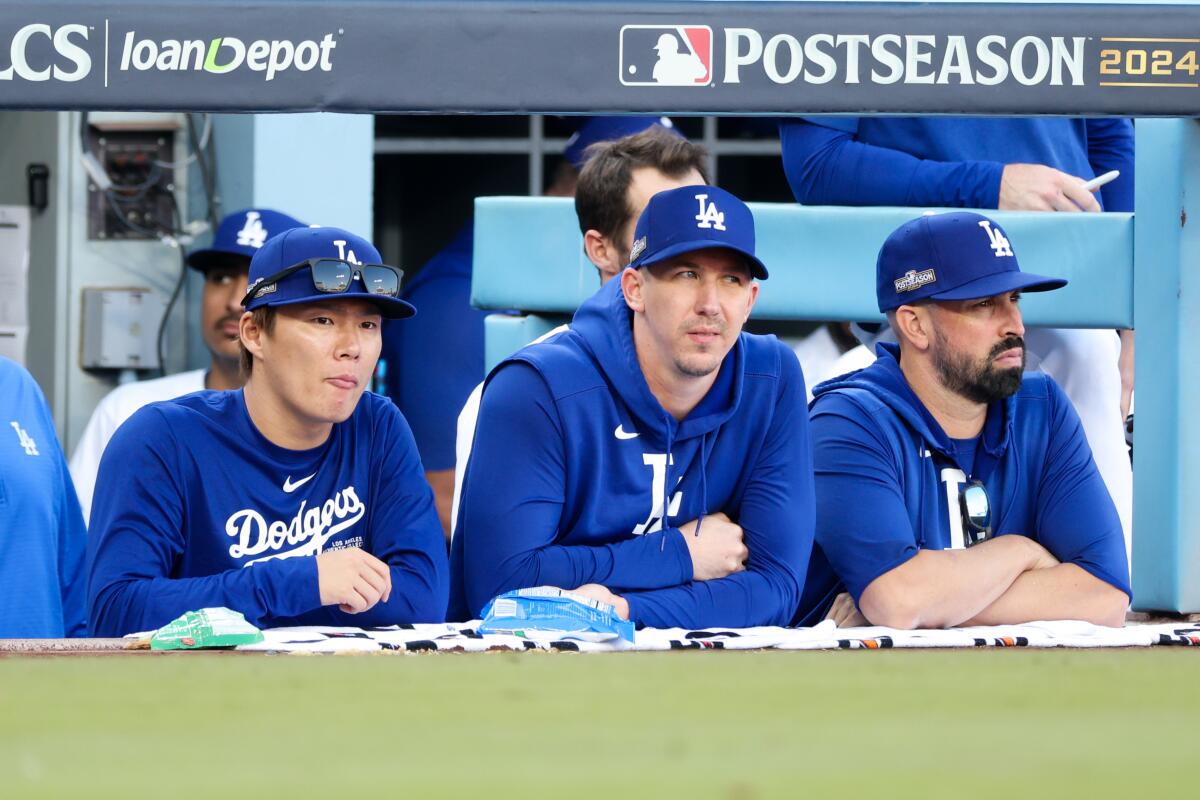 Dodgers pitchers Yoshinobu Yamamoto, left, and Walker Buehler, center, watch from the dugout at Dodger Stadium.