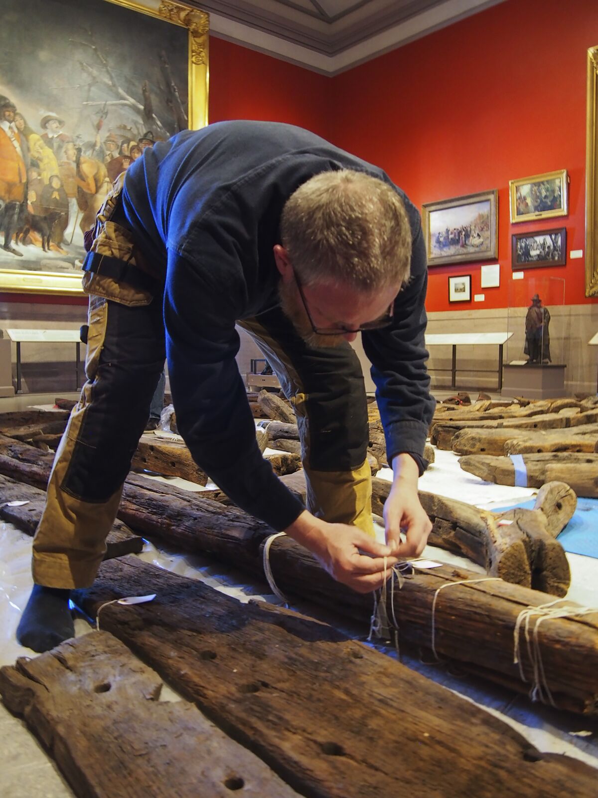 In this Jan. 2018 photo provided by the Pilgrim Hall Museum, Dr. Fred Hocker, Director of Research, Vasa Museum, Stockholm, Sweden, examines Sparrow-hawk timbers at Pilgrim Hall Museum, in Plymouth, Mass. The timbers were sampled in 2018 and analyzed over the course of several years. (Marie Pelletier/Pilgrim Hall Museum photo via AP)