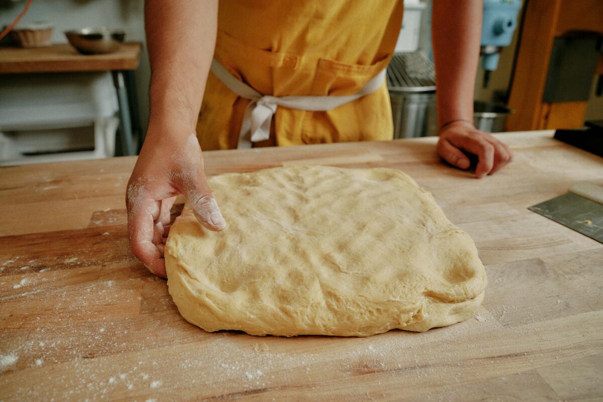 Patting the pan de muerto dough into a rectangular shape