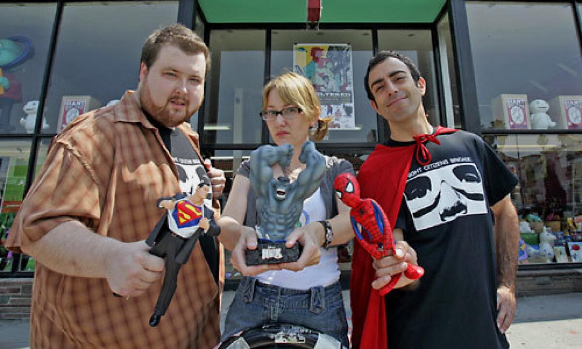 (L-R) Justin Donaldson, Linda Pine and Hal Rudnick, co-producers of Tournament of Nerds, show off a few of their favorite superheroes in front of Meltdown Comics & Collectibles. The tournament features comic book fans debating the merits of various superheroes in a bracket-style competition.