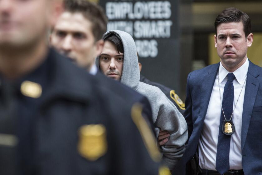 Not so brash anymore: Pharmaceutical pariah Martin Shkreli (in gray hoodie), escorted by federal agents after his arrest for fraud Thursday.