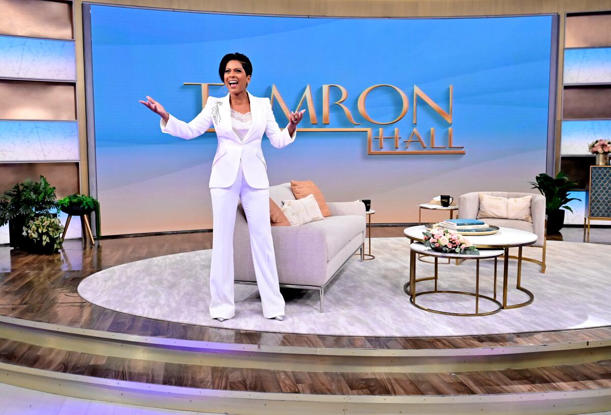 Tamron Hall, in white pantsuit, on the set of her ABC show