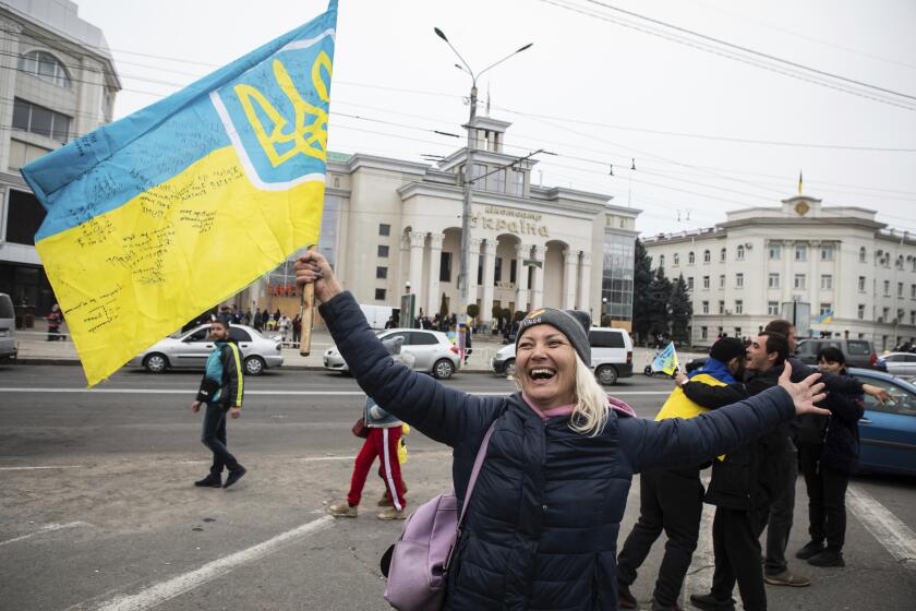 Ukrainians gather in downtown to celebrate the recapturing of their city Kherson, Ukraine, Saturday, Nov. 12, 2022. People across Ukraine awoke from a night of jubilant celebrating after the Kremlin announced its troops had withdrawn to the other side of the Dnieper River from Kherson. The Ukrainian military said it was overseeing "stabilization measures" around the city to make sure it was safe. (AP Photo/Yevhenii Zavhorodnii)