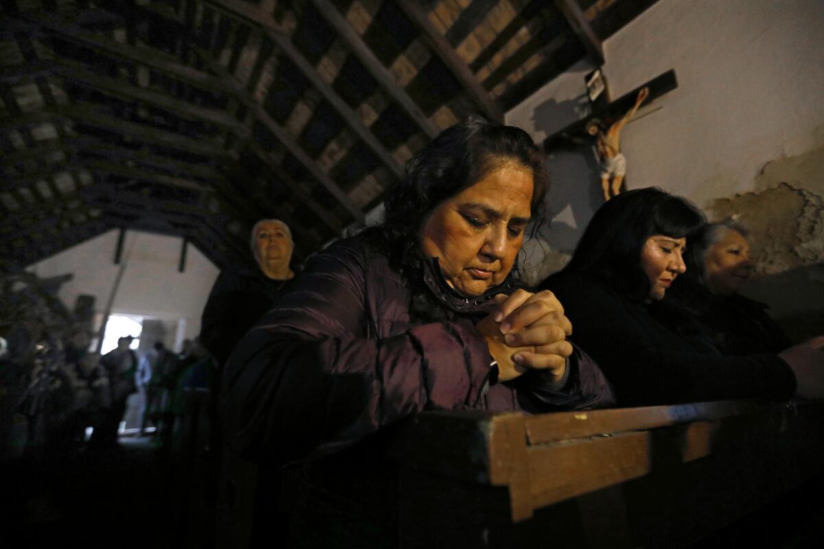Elizabeth Garcia, center, and Anna Velasquez, right, pray during Mass at La Lomita chapel in Mission, Texas.