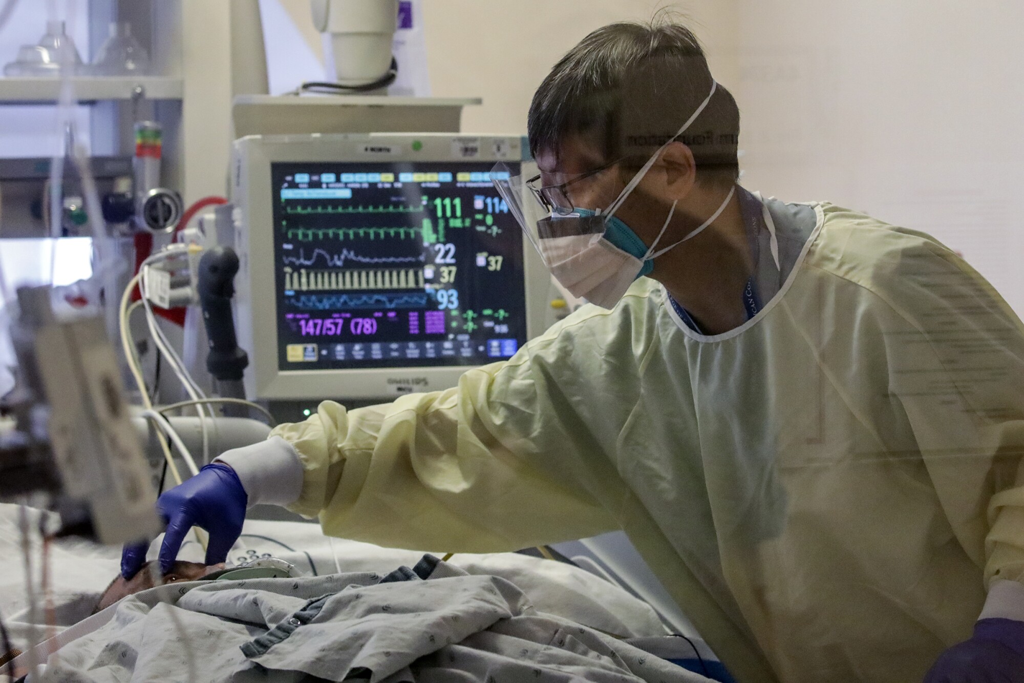 دکتر دیوید وانگ یک بیمار مبتلا به کووید را در مرکز پزشکی منطقه ای Arrowhead معاینه می کند.