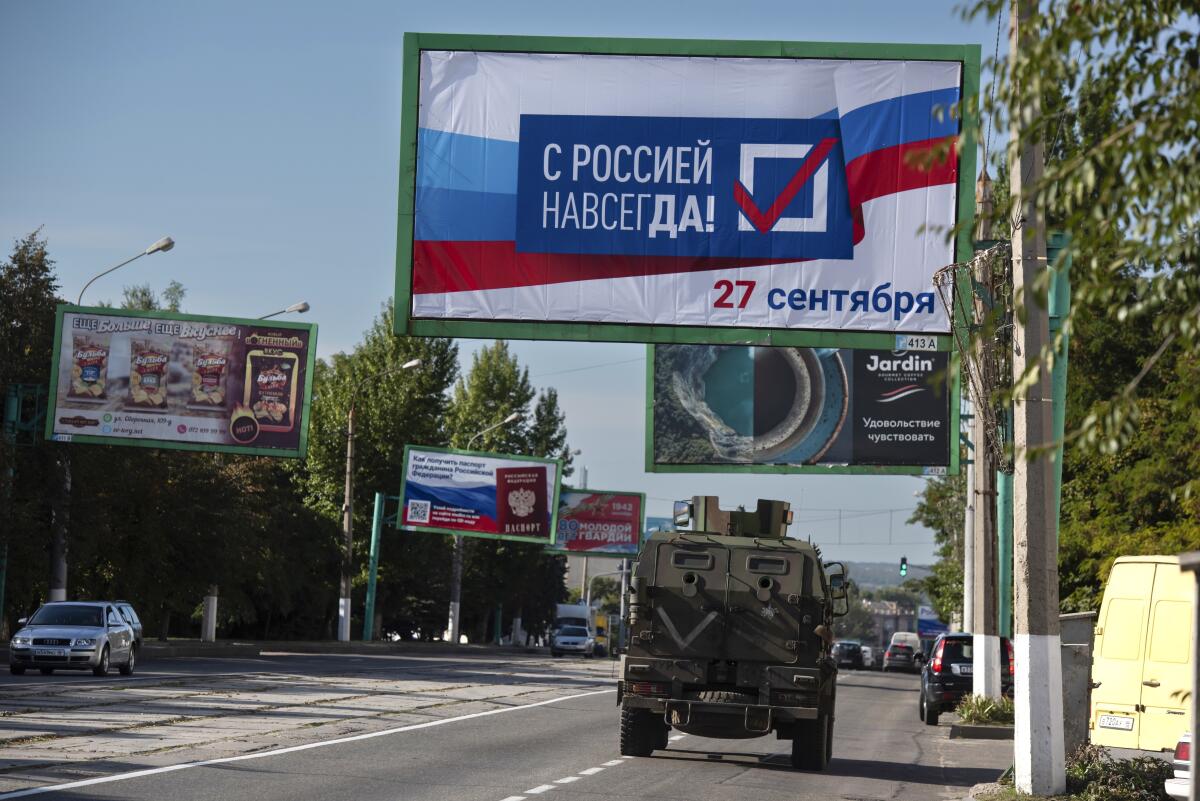 A roadside billboard in a city reads in Cyrillic, "With Russia forever! September 27" 