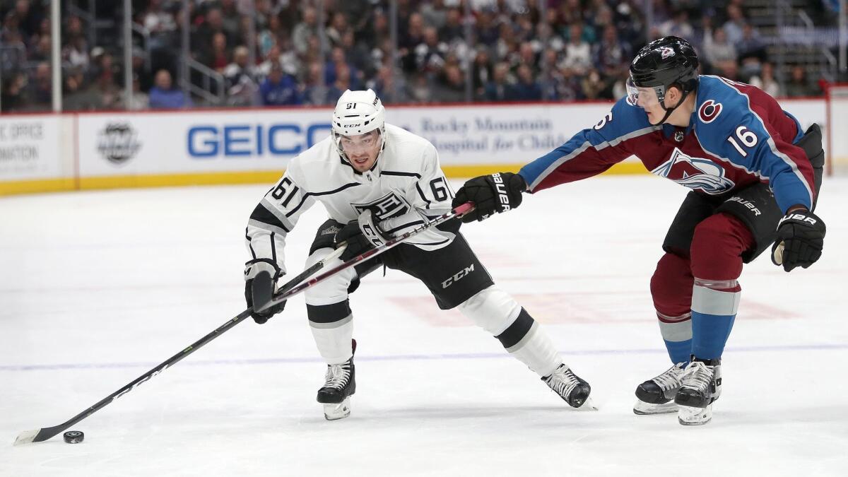 Kings' Sean Walker fights for control of the puck against Colorado Avalanche's Nikita Zadorov in the first period on Jan. 19 in Denver.