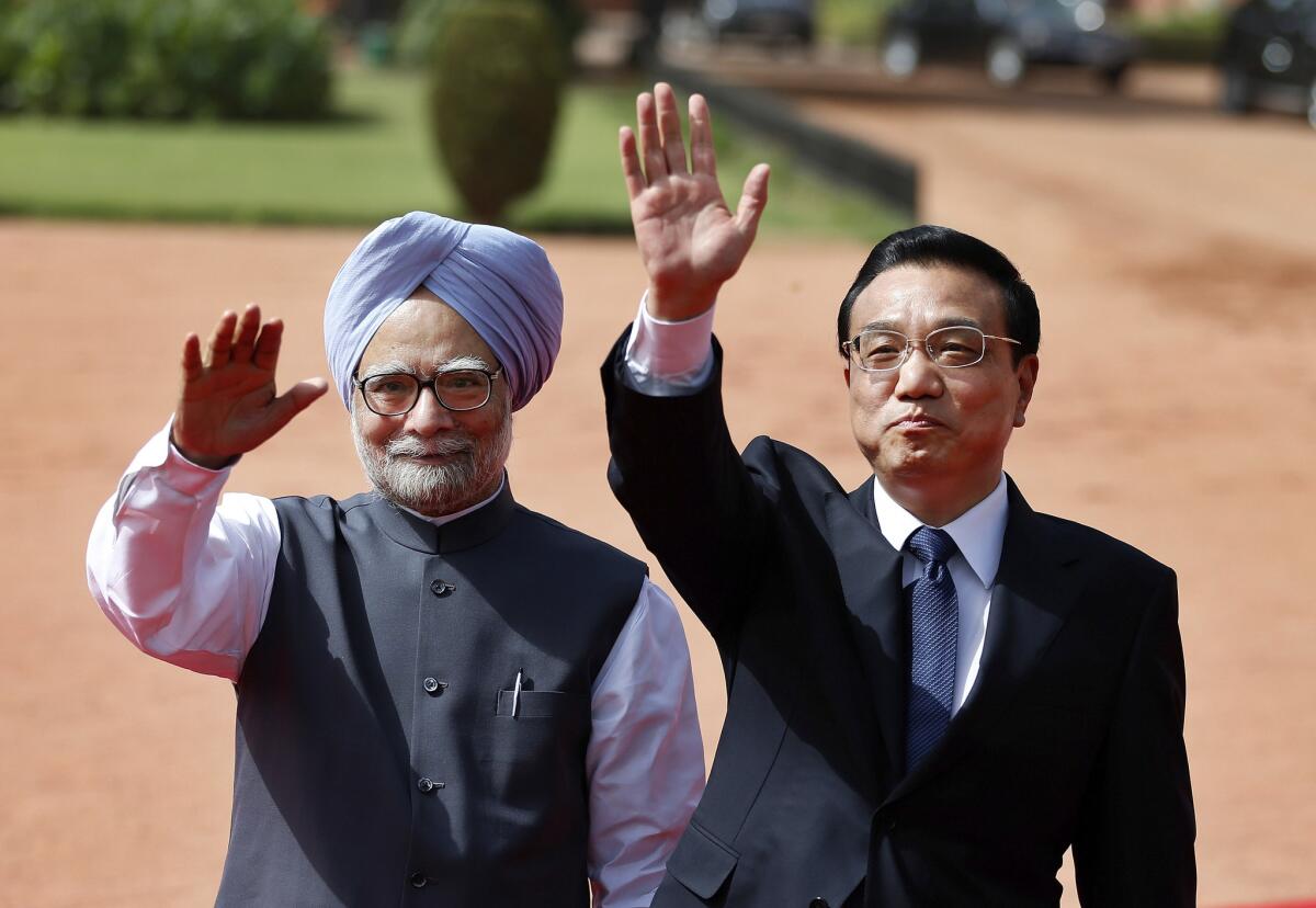 Chinese Premiere Li Keqiang, right, and Indian Prime Minister Manmohan Singh wave during a ceremonial reception for Li in New Delhi on Monday.