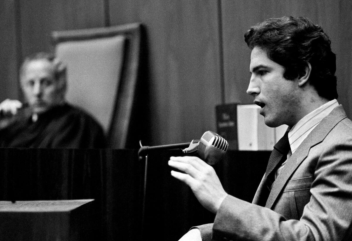 Black-and-white photo of a man talking in court 