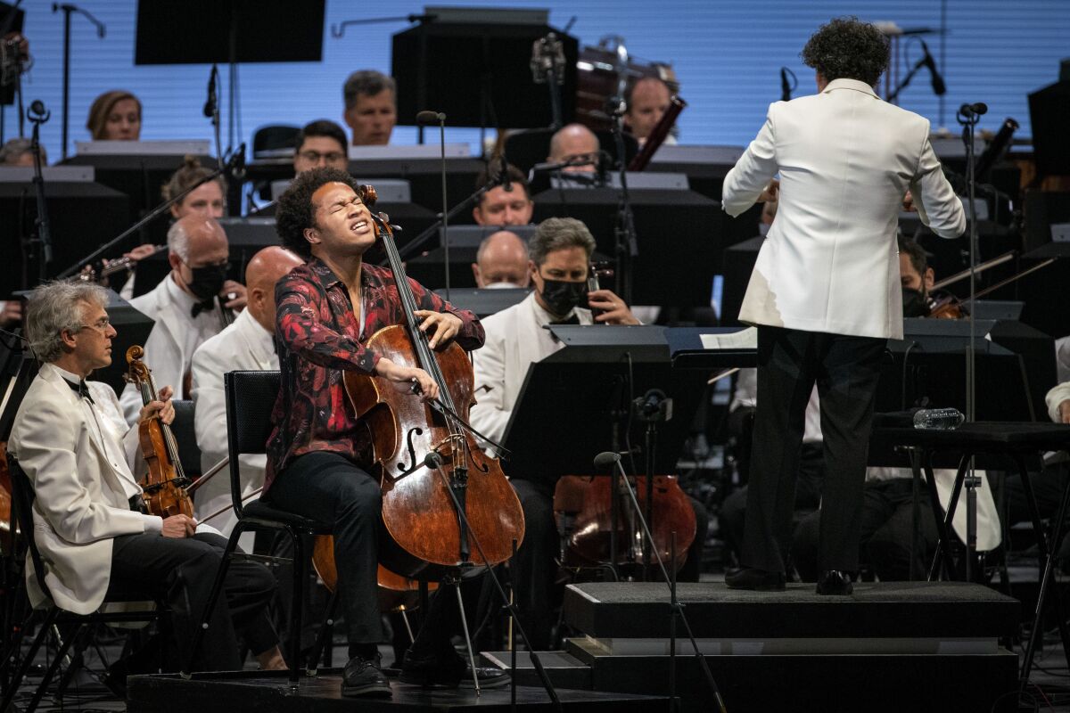 Sheku Kanneh-Mason plays his cello as Gustavo Dudamel conducts musicians.