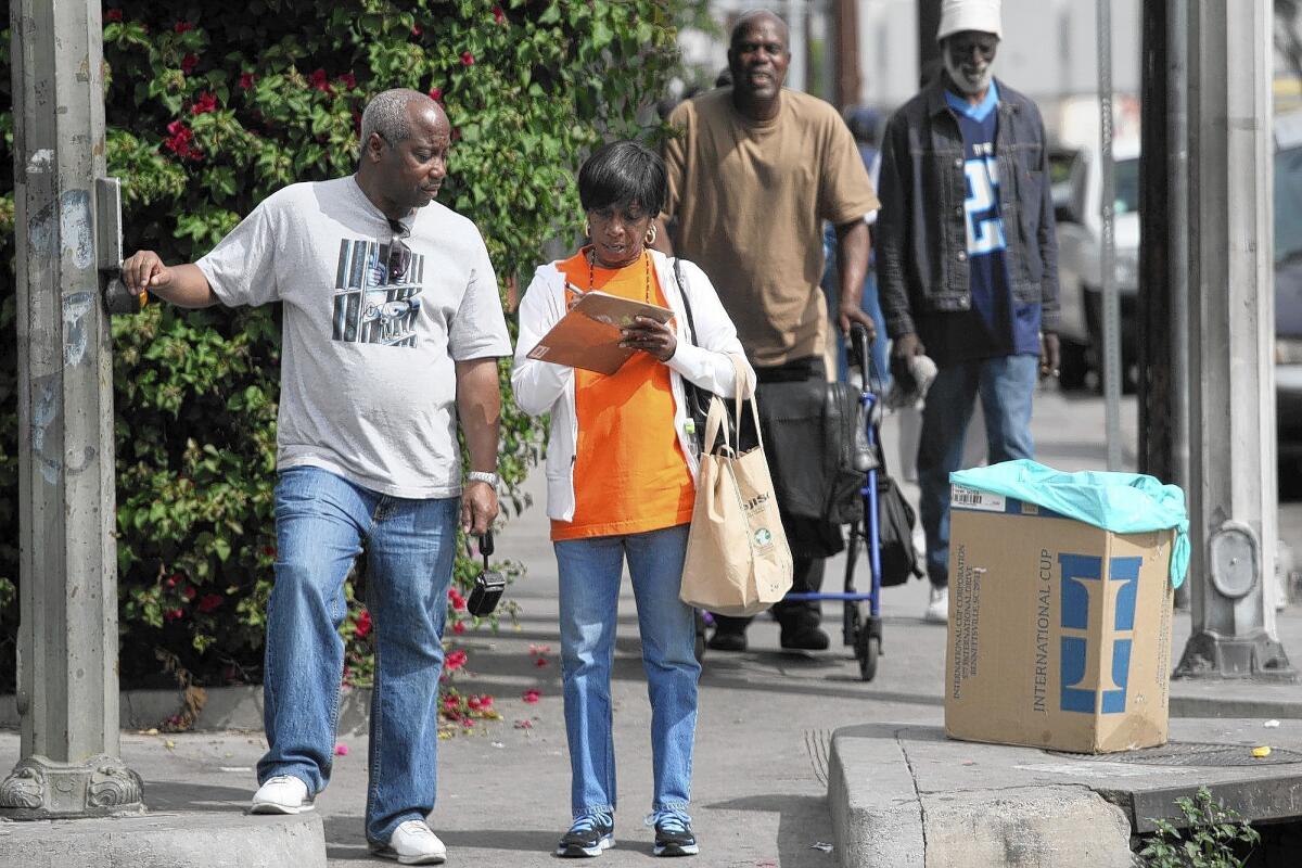 Activist Deborah Burton, right, walks with Carl Scott along skid row in downtown Los Angeles. Burton and her group — the Los Angeles Community Action Network — have filed a federal civil rights lawsuit against the city, alleging that police have conspired with business leaders to quash protest on skid row.