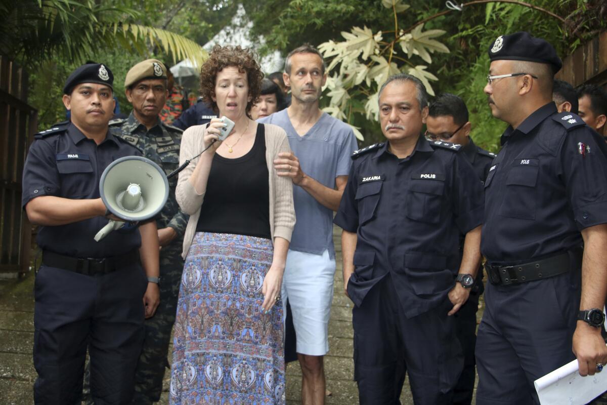 FILE - In this Aug. 10, 2019, file photo, Meabh Quoirin, center left, the mother of then missing girl Nora Anne Quoirin, speaks to police officers as father Sebastien Quoirin, center right, stands beside her in Seremban, Negeri Sembilan, Malaysia. Quoirin said Wednesday, Nov. 11, 2020, that criminal evidence may have been lost as police were slow to act on the possibility that her daughter could have been abducted. (Malaysia Information Ministry via AP)