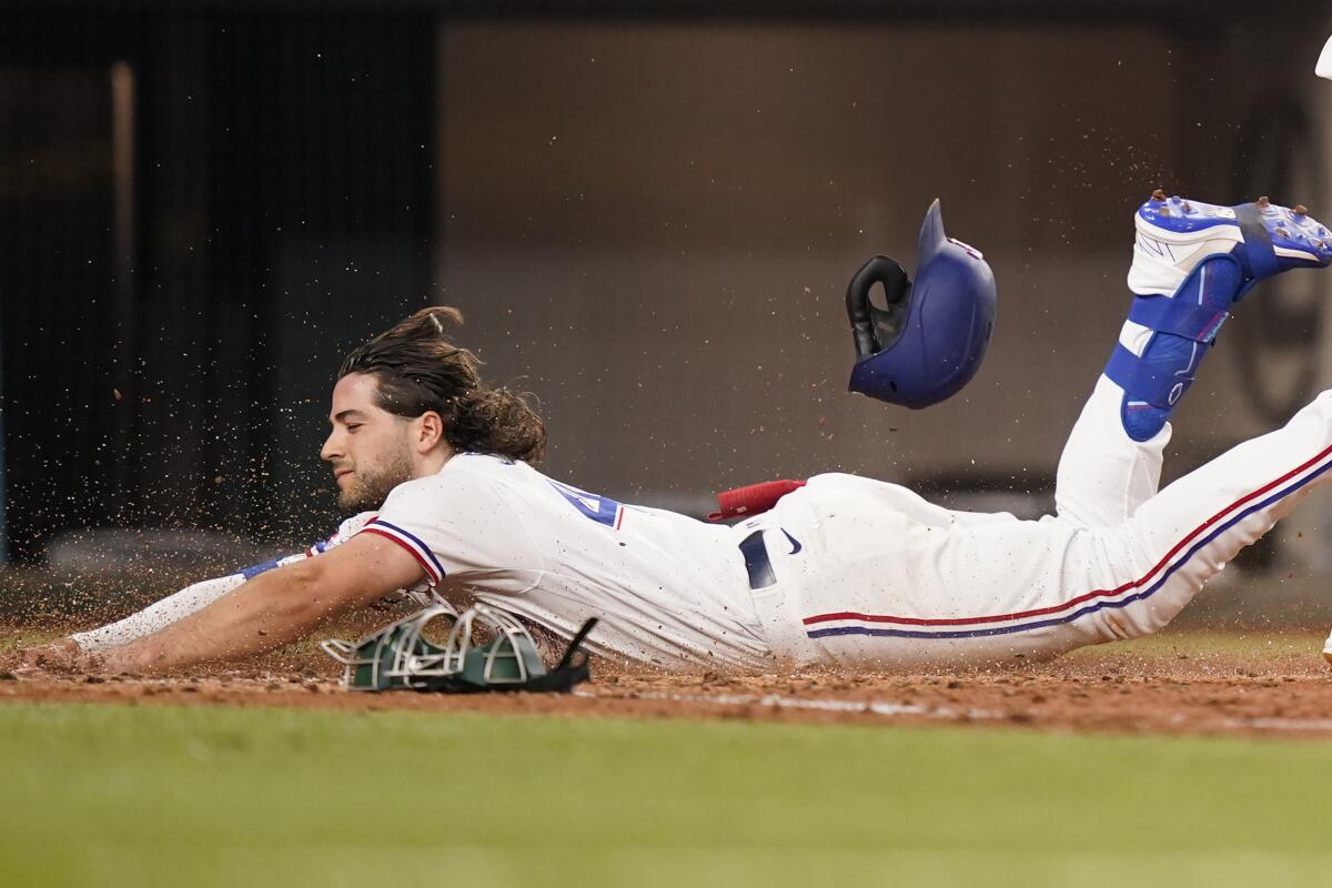 Texas Rangers Josh Smith slides safely into home plate for an inside-the-park home run during the sixth inning of a baseball game against the Oakland Athletics in Arlington, Texas, Monday, July 11, 2022. Rangers' Leody Taveras also scored on the play. (AP Photo/LM Otero)