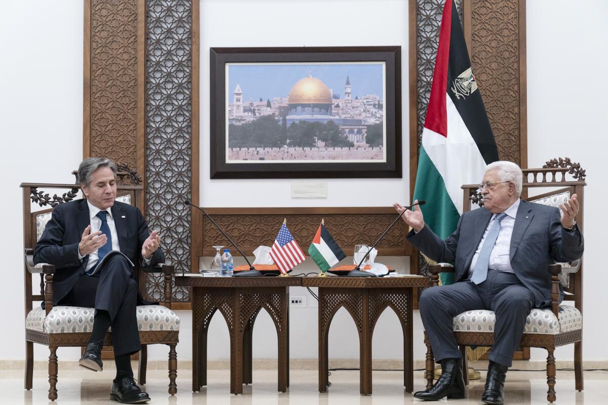 Antony Blinken, left, and Mahmoud Abbas, both seated, gesture as they speak