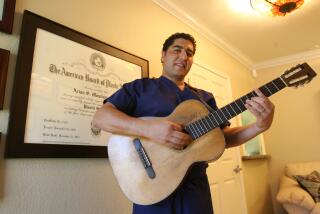 2008 photo of Dr. Arian Mowlavi playing guitar in his South Laguna office.