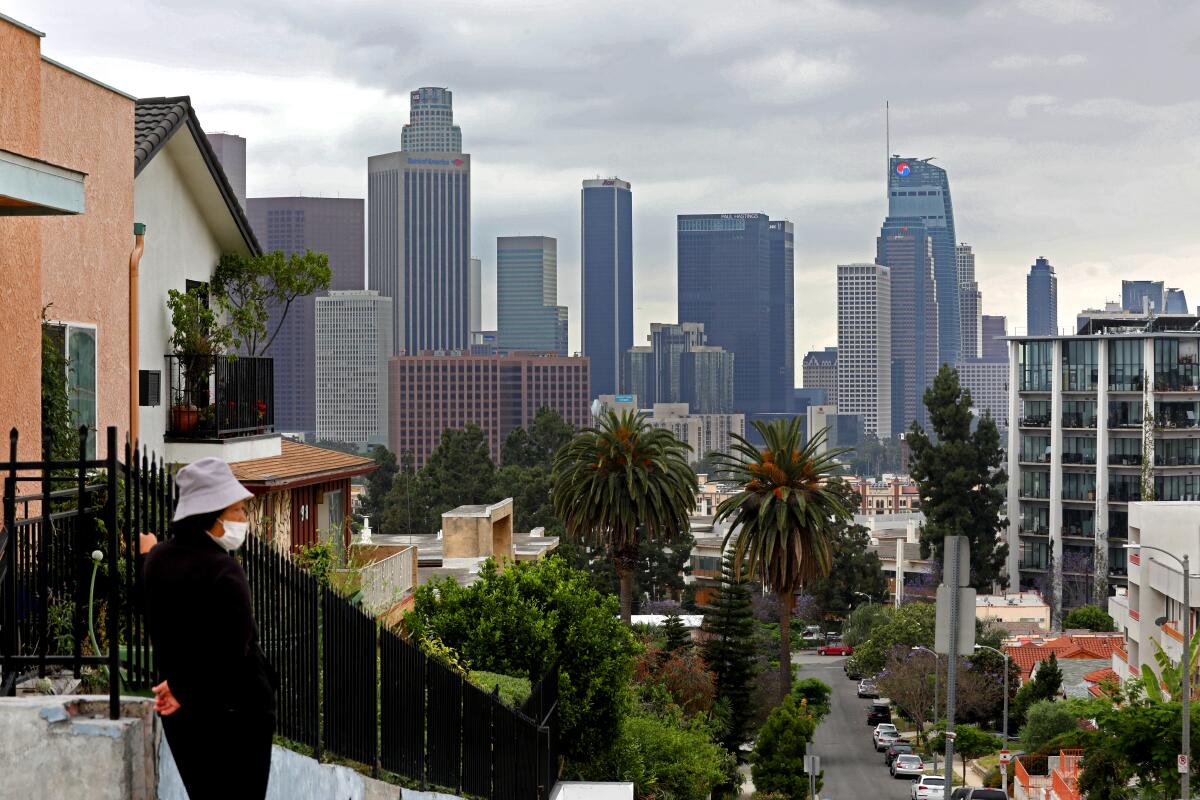 Gray skies loom over downtown Los Angeles as a woman pauses on a walk.