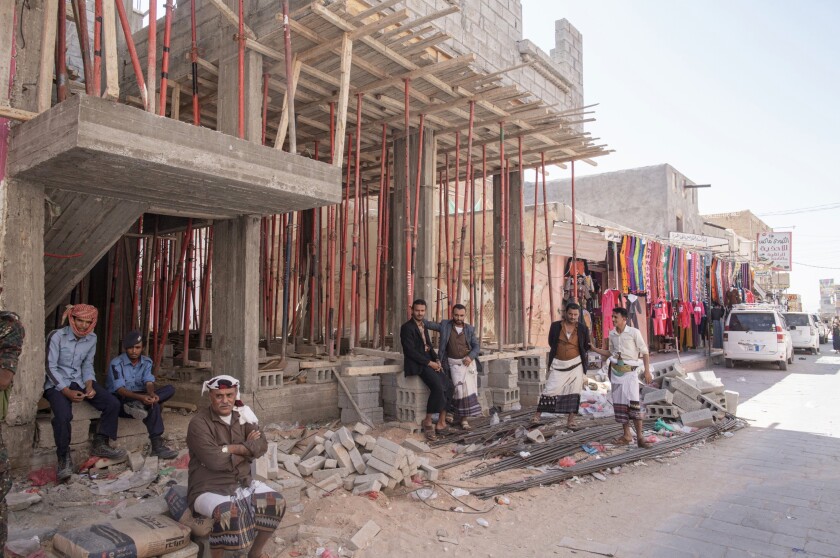 Men sit outside a construction site in the market area of Ataq, in Shabwa Province, Yemen.