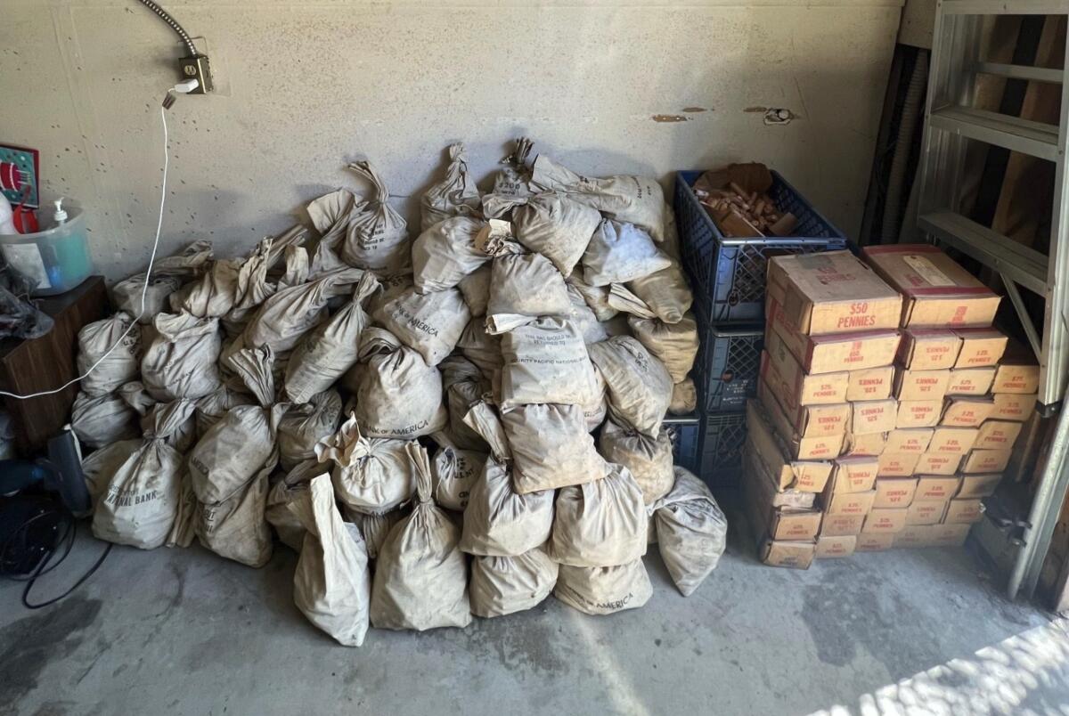 A pile of bags sits next to boxes on a concrete floor