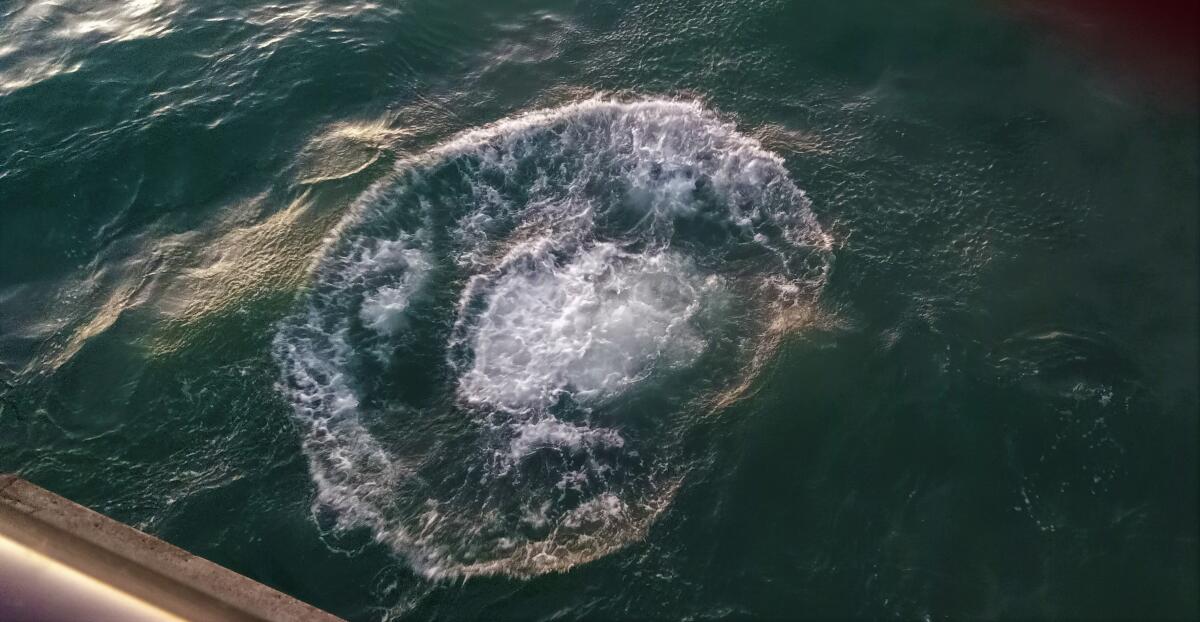 A splash in the ocean seen from a pier above