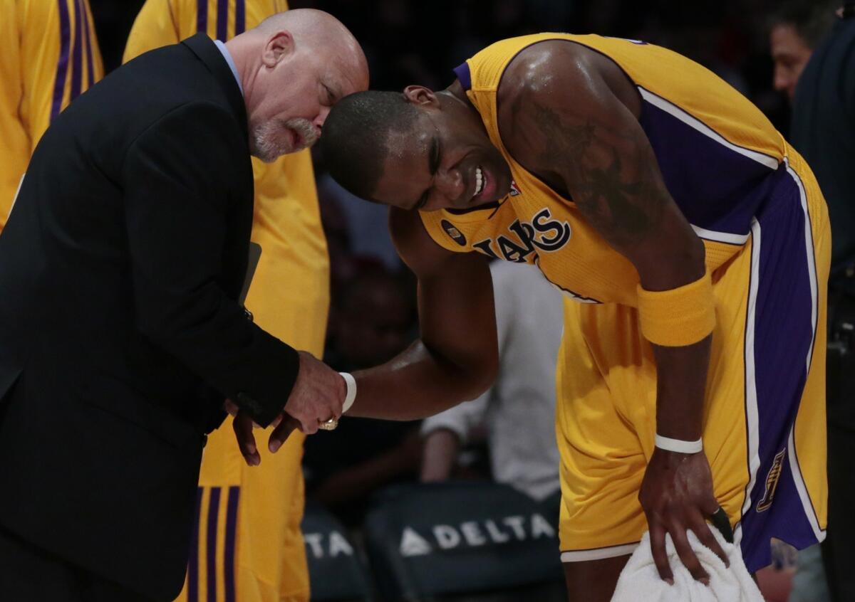 Lakers forward Antawn Jamison grimaces in pain Friday as trainer Gary Vitti looks at his injured wrist.