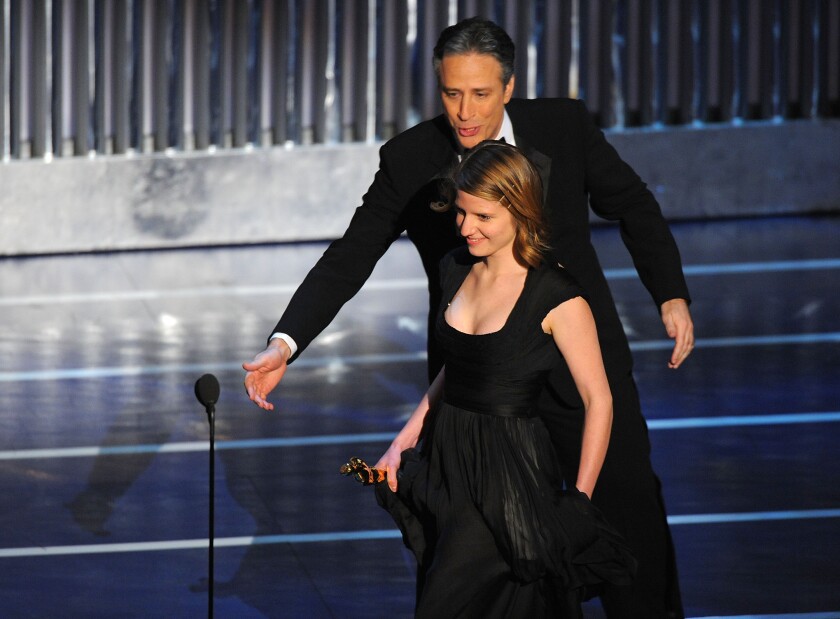 A man ushers a woman to a microphone