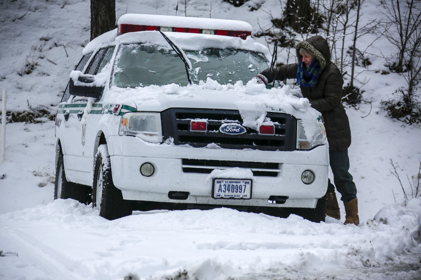 Diane Travis of Angeles Forest service removes snow from her vehicle above Wrightwood at Mountain High.