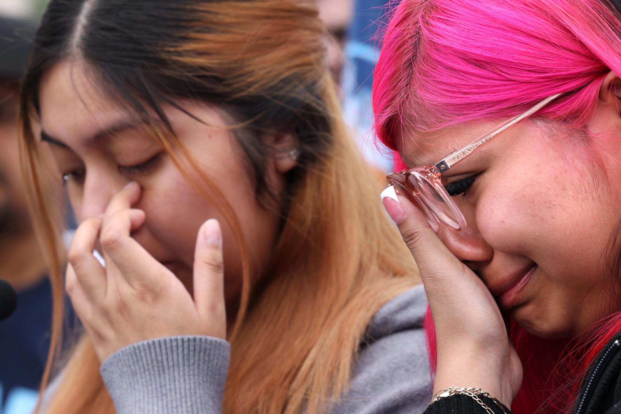 Sisters, one with brown hair and one with pink hair, cry when talking about their father.