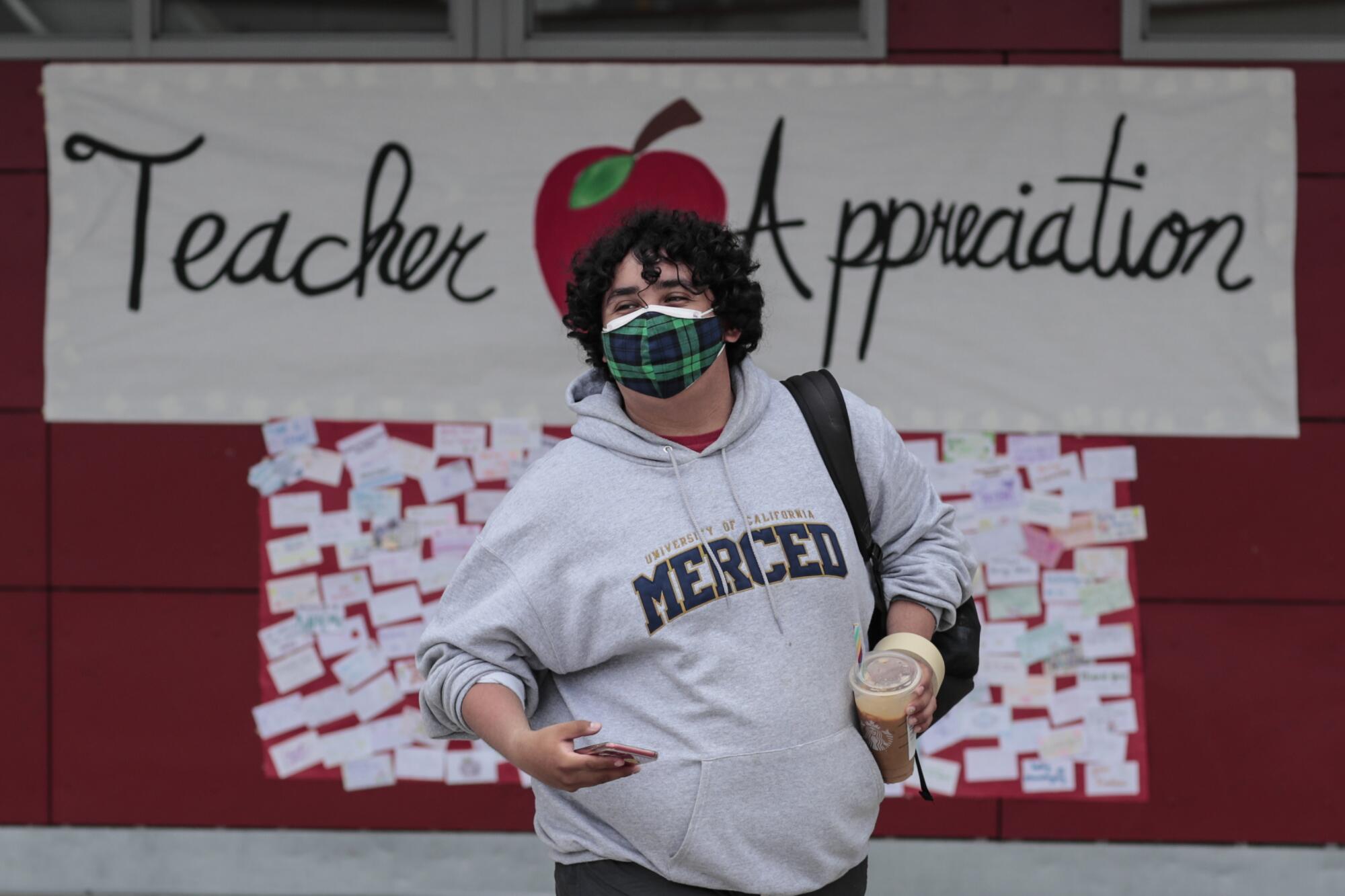 Starbucks in one hand, smartphone in the other, Jesus Medina looks for teachers arriving on campus at Sierra Vista High