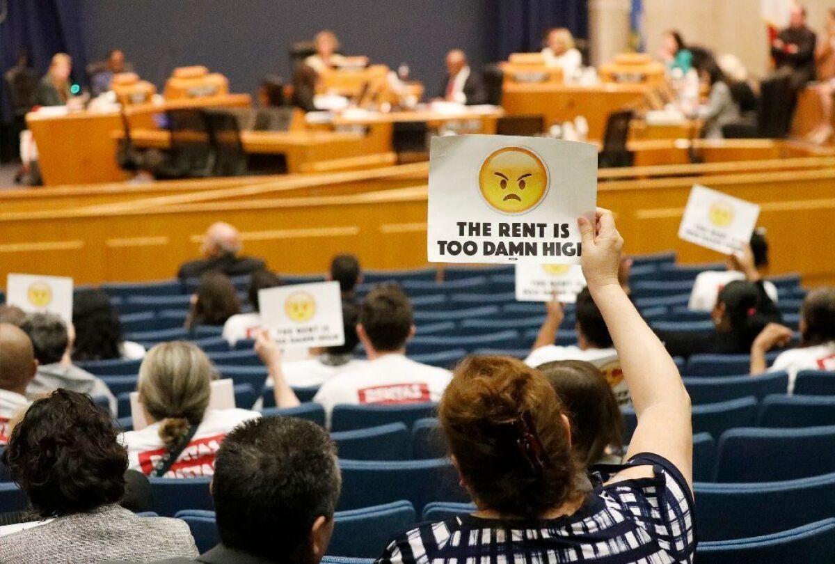 Beatrice Sandoval holds up a sign at an L.A. County Board of Supervisors meeting in April as the board voted to extend a temporary cap on rent increases through 2019. The cost of housing is a drag on Angelenos' quality of life, a UCLA survey found.