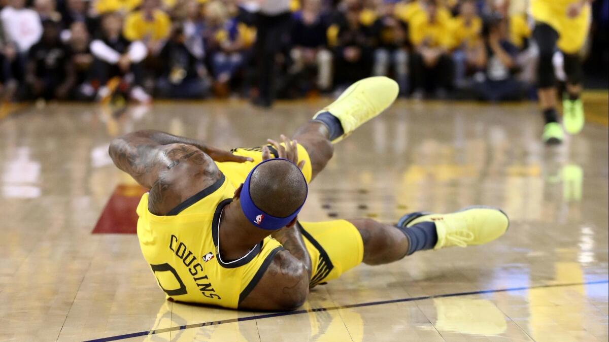 Warriors center DeMarcus Cousins grabs his left thigh after falling to the court while chasing a loose ball during Game 2 on Monday.