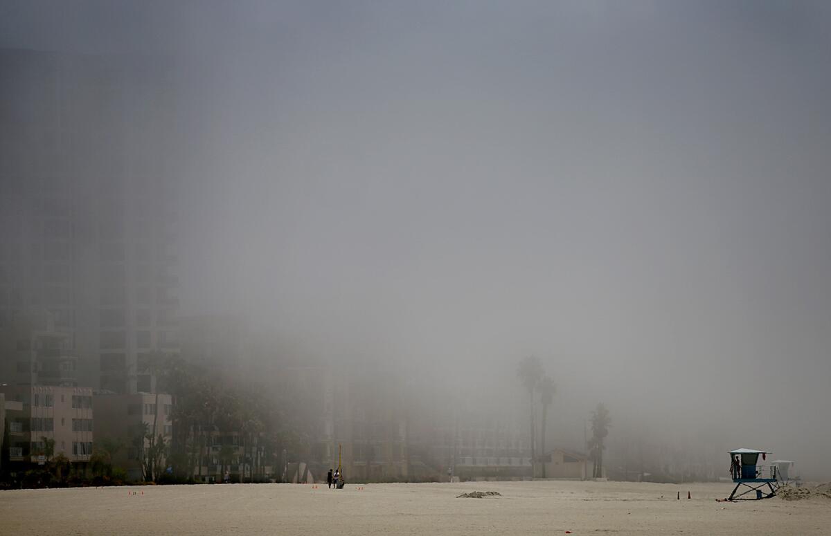 A lifeguard opens a station as the sun breaks through the lifting marine layer on a June morning in 2013. A marine layer covered the Los Angeles area Tuesday, and rain is expected by midweek.