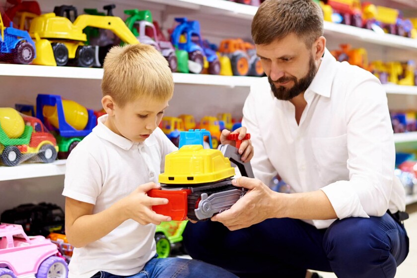 A father and son examine a colorful toy truck in a store