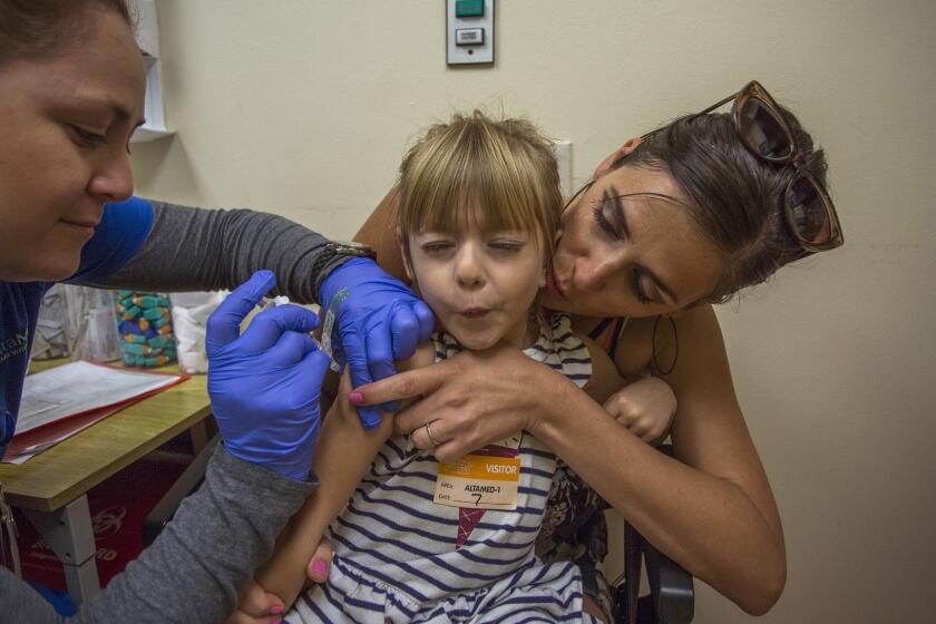 LOS ANGELES-CA-AUGUST 7, 2017: Raven Summers, 4, holds her breath in the arms of her mother Jessica Summers as Medical Technician Lilliana Lopez gives her a vaccination at Children's Hospital Los Angeles in advance of the new school year in Los Angeles, California, August 7, 2017. Vaccination rates in California went up after the state passed the one of the strictest vaccinations laws in the country, but there are still pockets where not enough kids are getting vaccinated. (David McNew / For The Times)