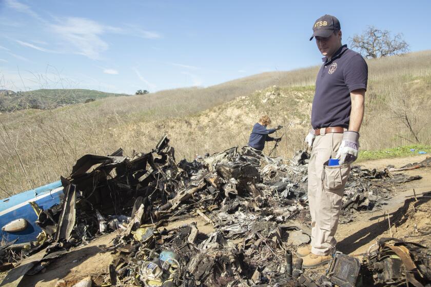 In this image taken Monday, Jan. 27, 2020, and provided by the National Transportation Safety Board, NTSB investigators Adam Huray, right, and Carol Hogan examine wreckage as part of the NTSB’s investigation of a helicopter crash near Calabasas, Calif. The Sunday, Jan. 26 crash killed former NBA basketball player Kobe Bryant, his 13-year-old daughter, Gianna, and seven others (James Anderson/National Transportation Safety Board via AP)