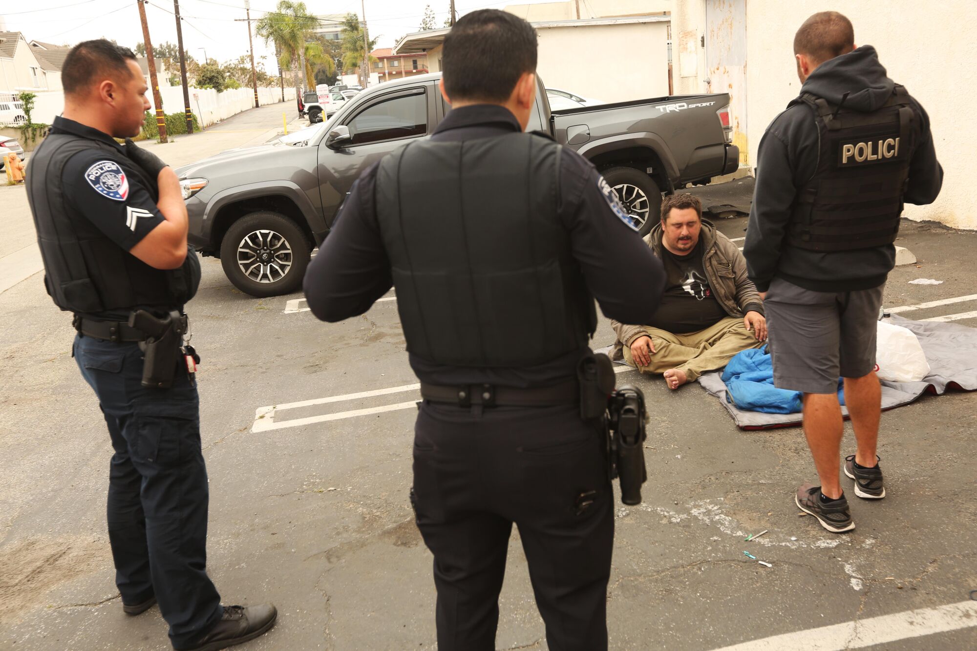 Torrance police officers talk with Andrew Truelove in the parking lot where he's been sleeping in Torrance. 