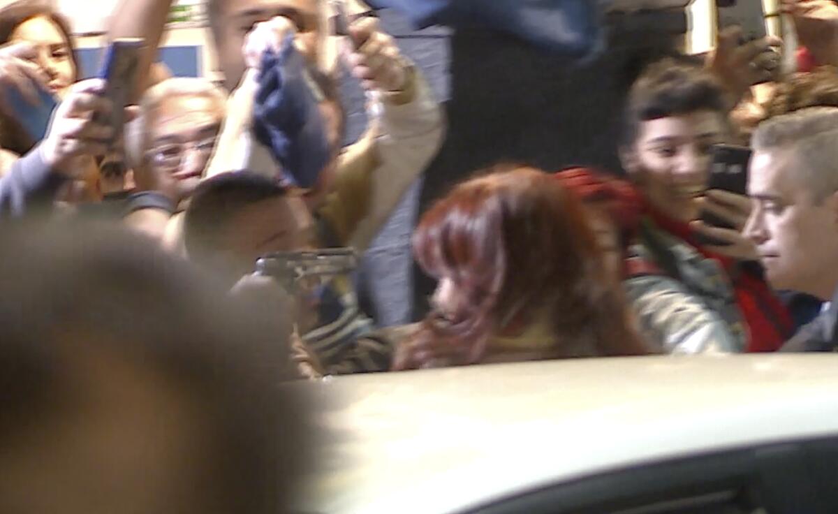 A blurry image taken from video of a man in a crowd pointing gun at Argentina's vice president