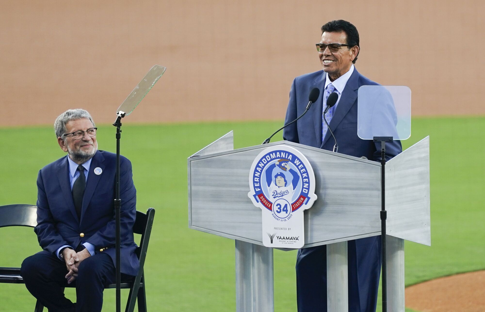 Charley Steiner looks on as Fernando Valenzuela speaks during his number retirement ceremony at Dodger Stadium.