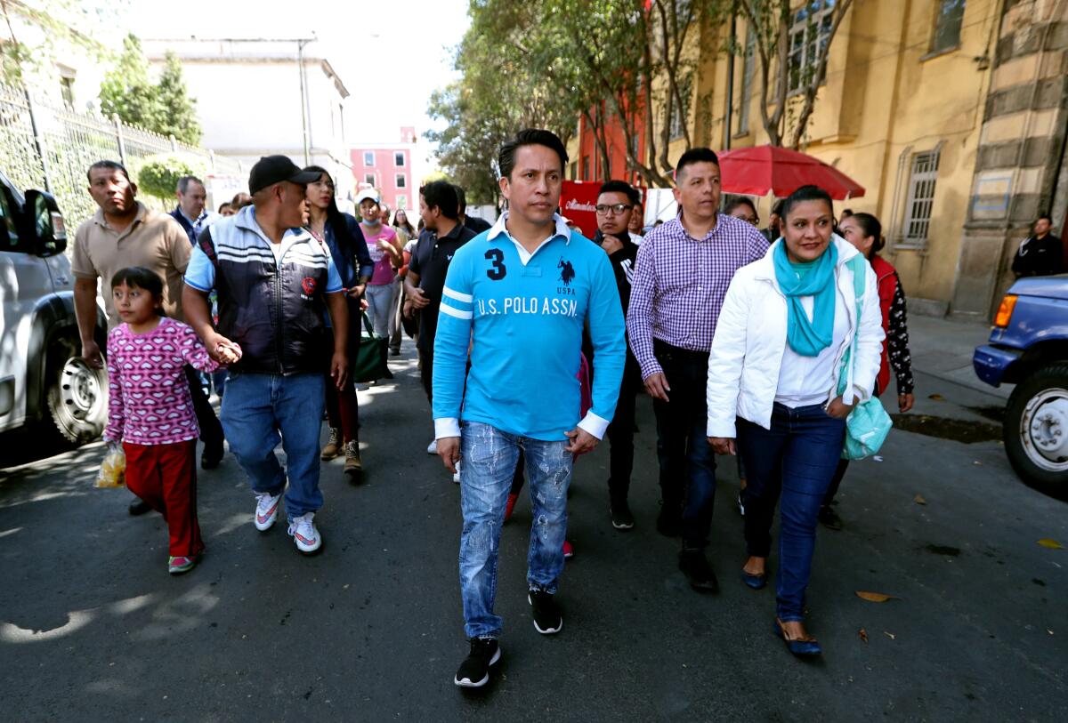 A crowd walks down a Mexico City street as parents of children with cancer protest.