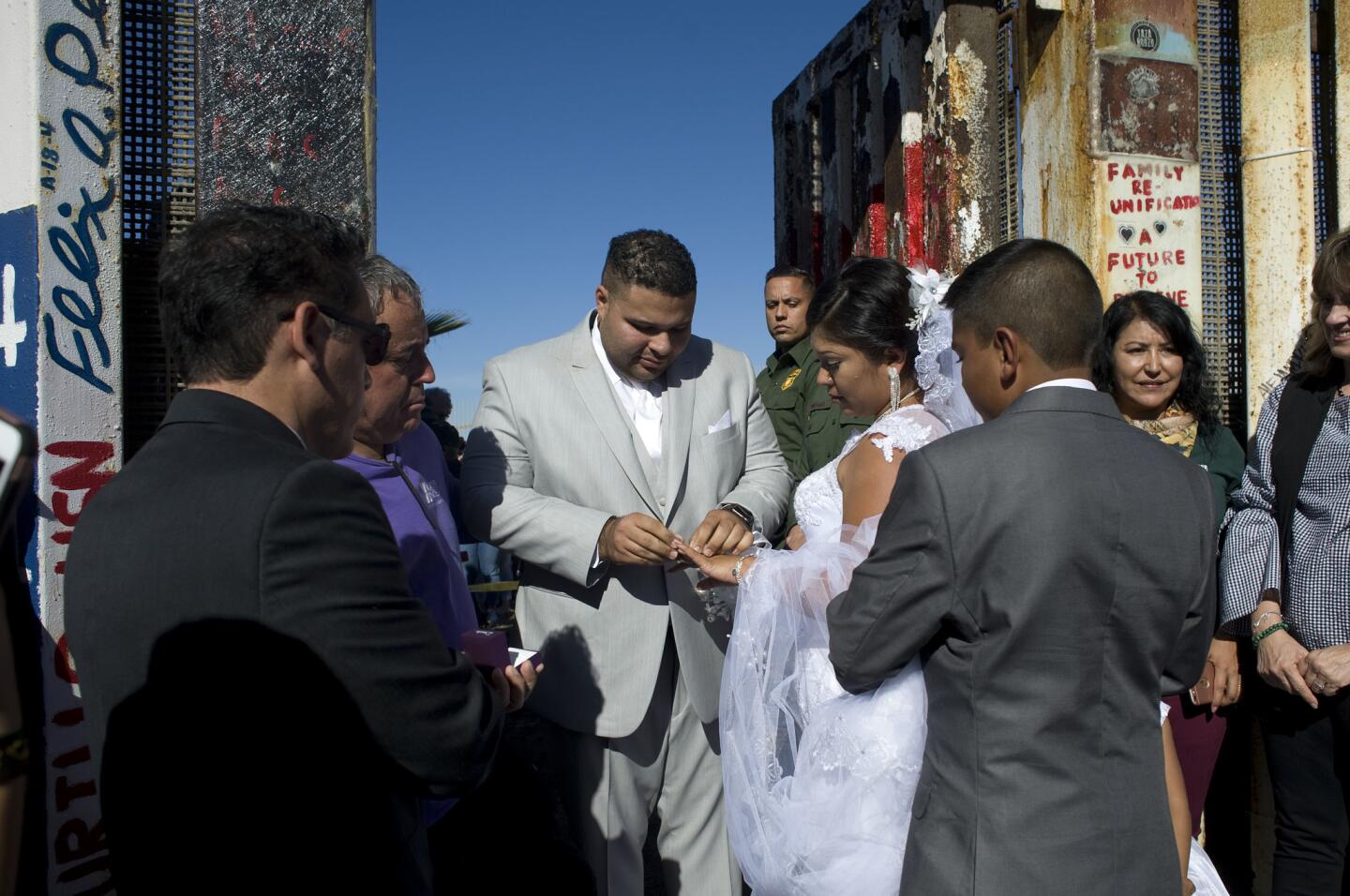 El estadounidense Brian Houston le pone un anillo a su prometida la mexicana Evelia Reyes durante la celebración de su boda en una de las puertas de la valla fronteriza entre EEUU y México en Tijuana, que abrió brevemente...