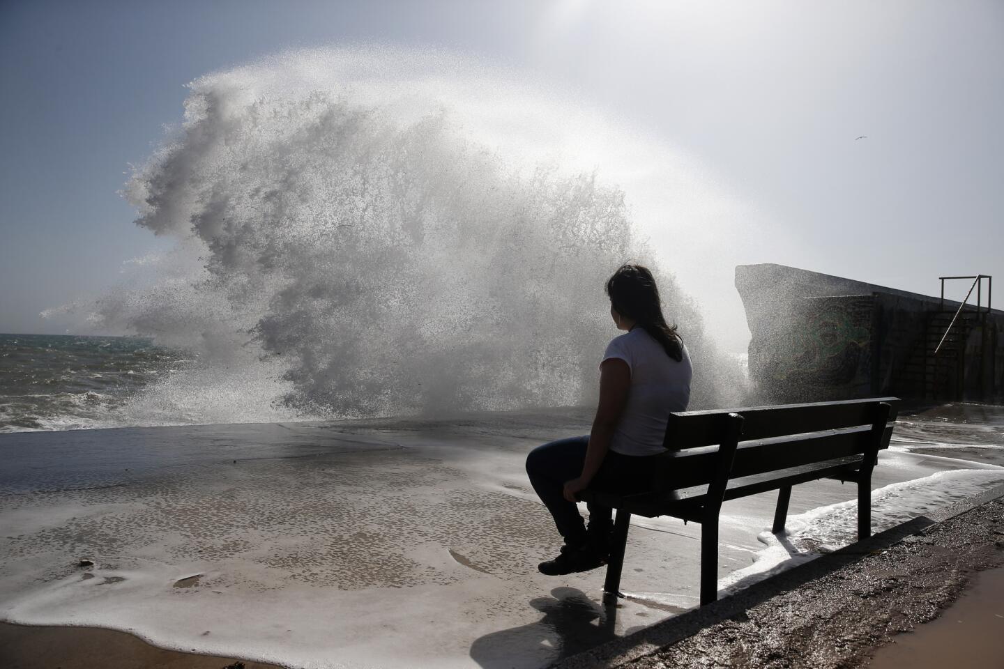 In the southern Athens coastal suburb of Flisvos, a woman braves wave splashes on a warm, windy afternoon.