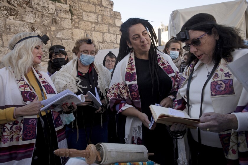 FILE - Members of Women of the Wall gather around a Torah scroll the group smuggled in for their Rosh Hodesh prayers marking the new month, at the Western Wall where women are forbidden from reading from the Torah, Sunday, Dec. 5, 2021. When Israel's new government took office last June, it indicated it would press ahead on an egalitarian prayer site at Jerusalem's Western Wall — a sensitive holy site that has emerged as a point of friction between Jews over how prayer is conducted there. (AP Photo/Maya Alleruzzo, File)