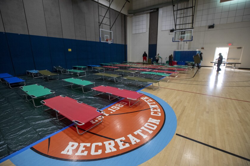 Salvation Army volunteer Christina Cuevas sets up cots for homeless people at Westwood Recreation Center.