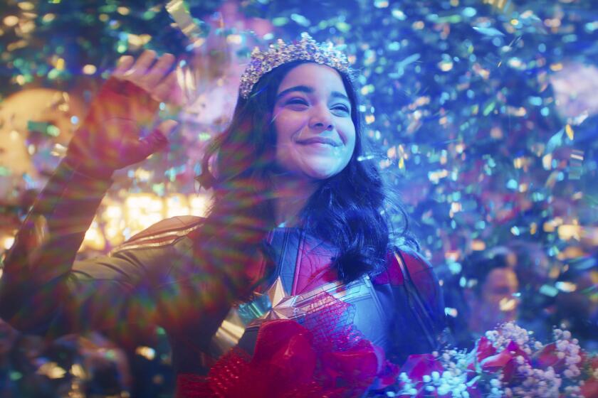 A teenage girl in a superhero costume and a tiara waving