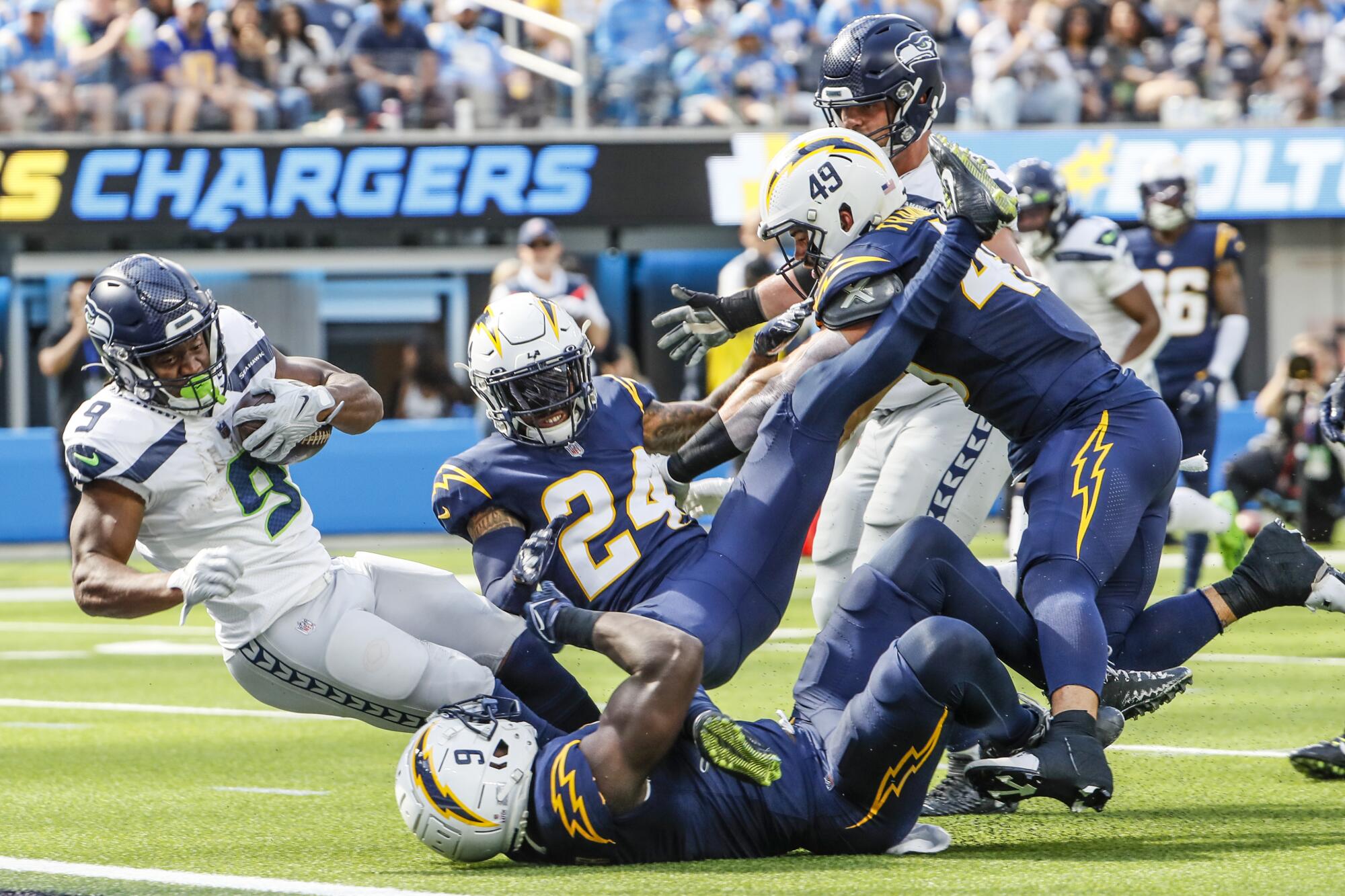 Seahawks running back Kenneth Walker III falls over Los Angeles Chargers linebacker Kenneth Murray Jr. (9) for a touchdown.