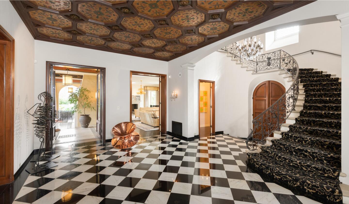 The foyer has curving steps to the second floor, black and white tiles and decorative ceiling.