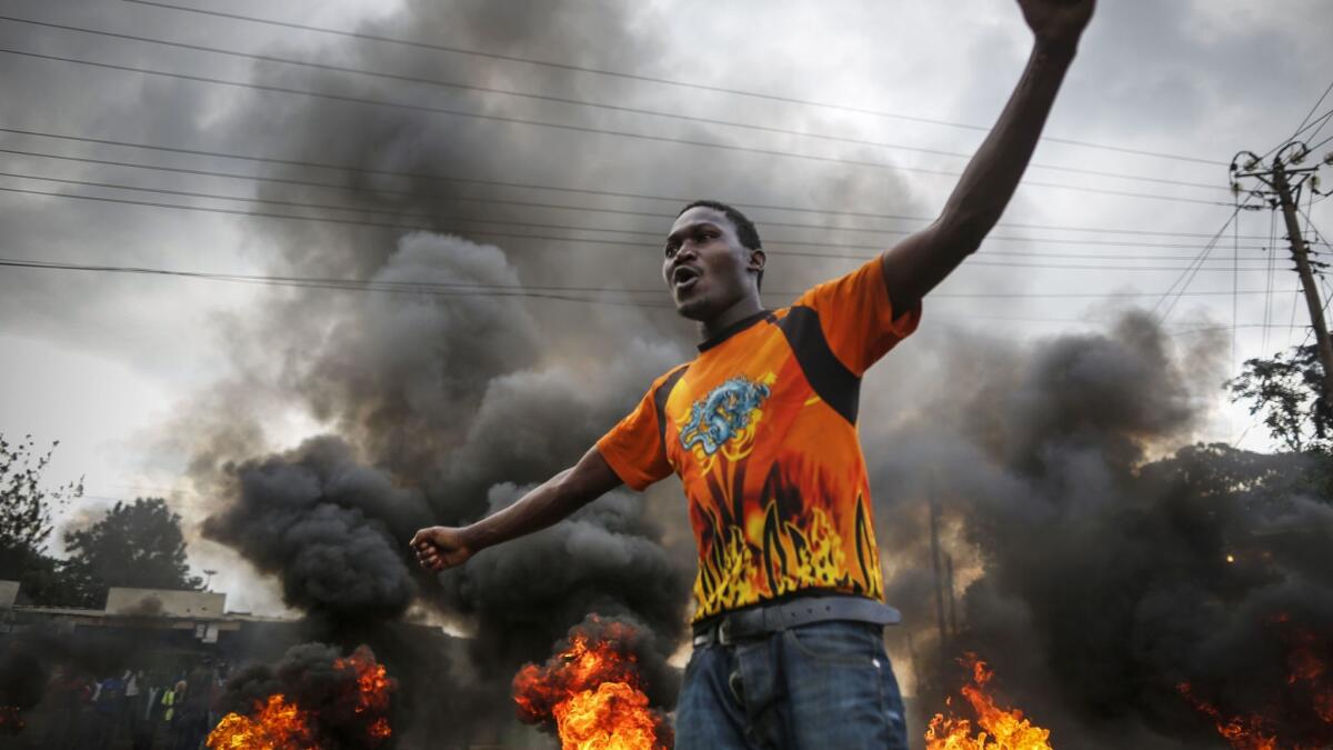 A supporter of presidential candidate Raila Odinga reacts in front of a burning barricade set up to block vehicles from delivering electoral materials to the polling stations in their areas in Kibera slum, one of the opposition strongholds in Nairobi, Kenya, on Oct. 25, 2017.