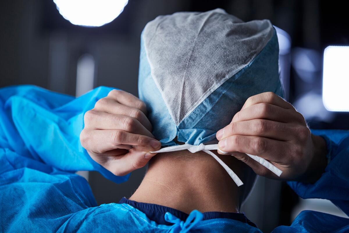 A surgeon ties the back of a surgical cap.