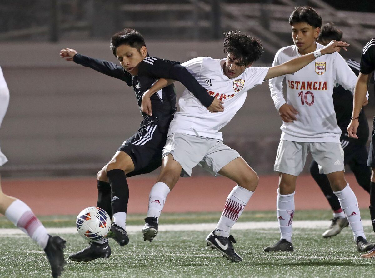 Costa Mesa's Kevin Perez-Cruz and Estancia's Esa Asmraz , from left, get tangled up as they battle for possession.